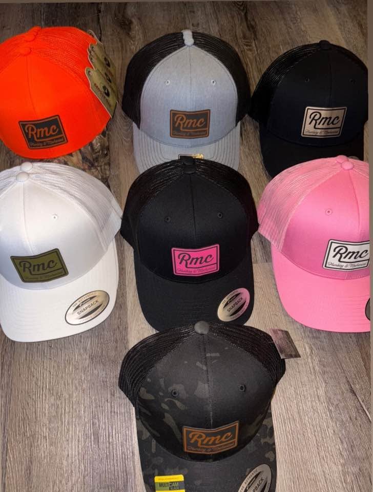 Assorted custom leather-patch baseball and trucker hats laid out on wood